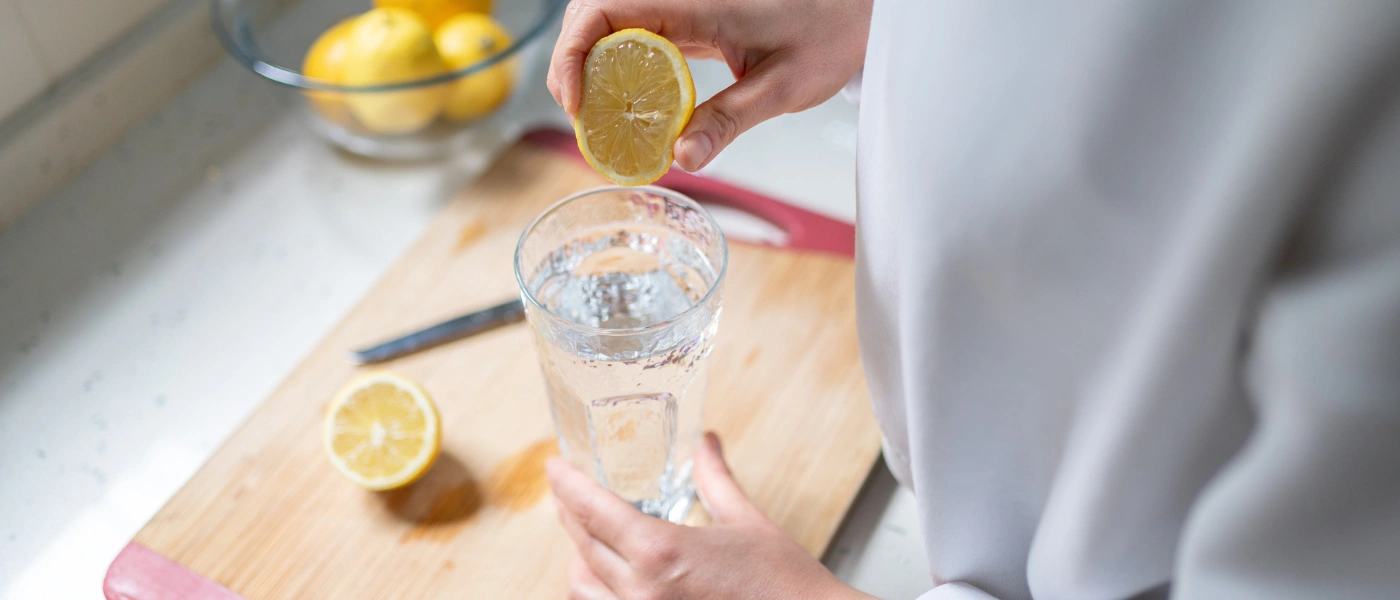 Zitrone über Glas mit Wasser pressen