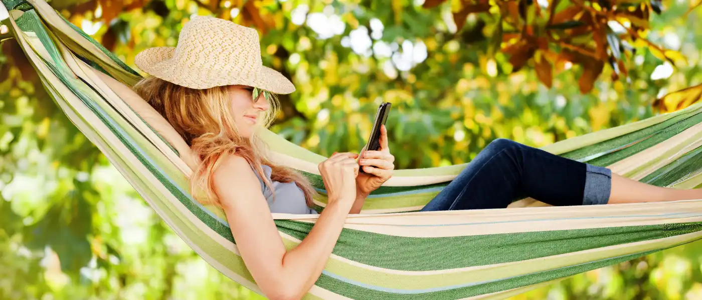 Frau entspannt in Hängematte mit Handy