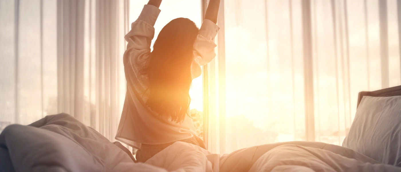 Frau streckt sich beim Sonnenaufgang im Bett