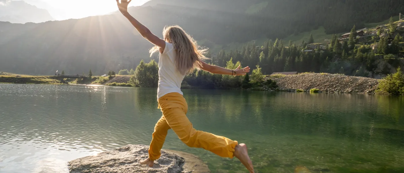 Frau springt über Felsen am Seeufer